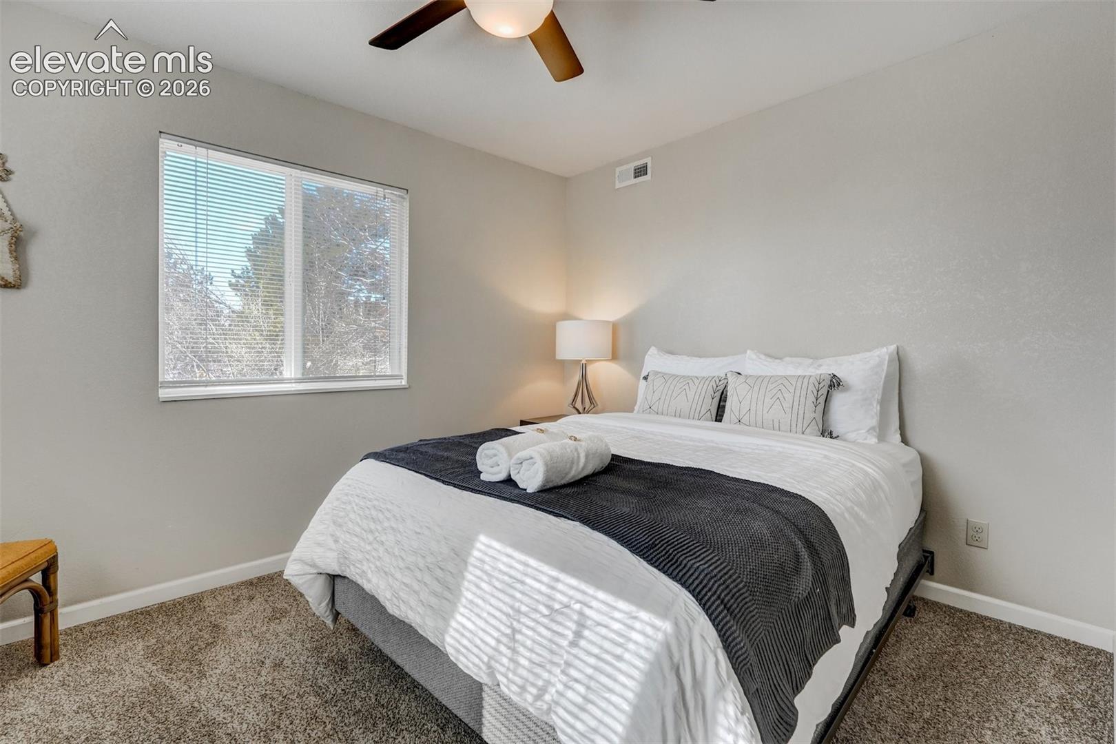 Carpeted room with a ceiling fan, a window with blinds, and neutral wall tones
