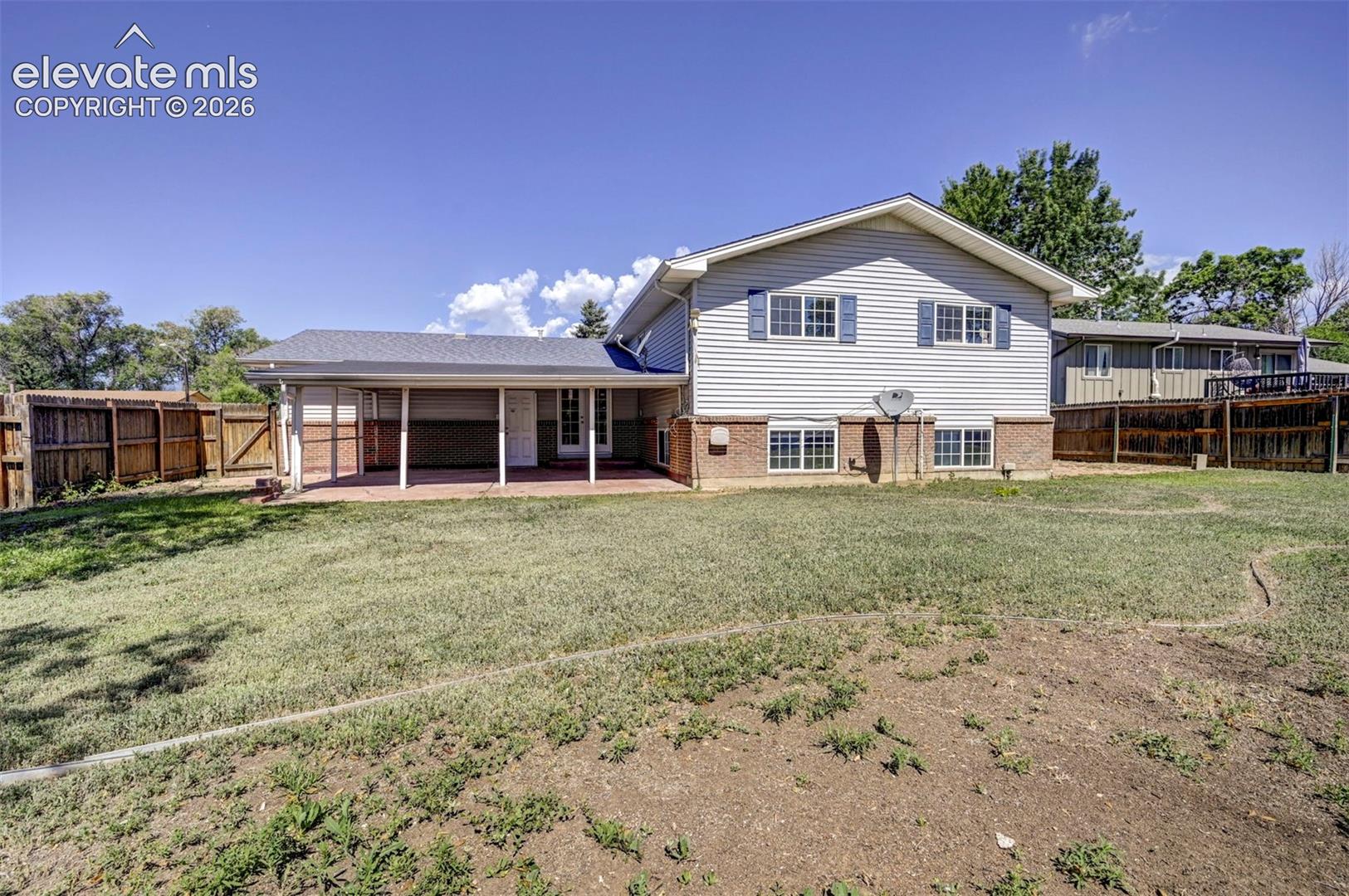Two-story exterior featuring horizontal siding, brick masonry, a covered patio, and wood privacy fencing