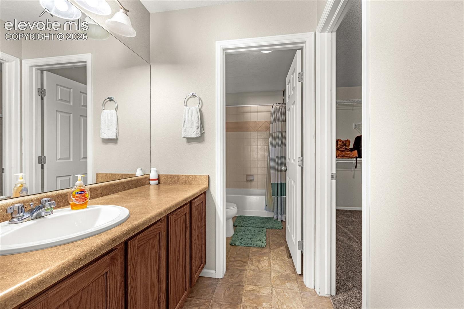 Vanity with an integrated sink, wood-finish cabinetry, and a large mirror