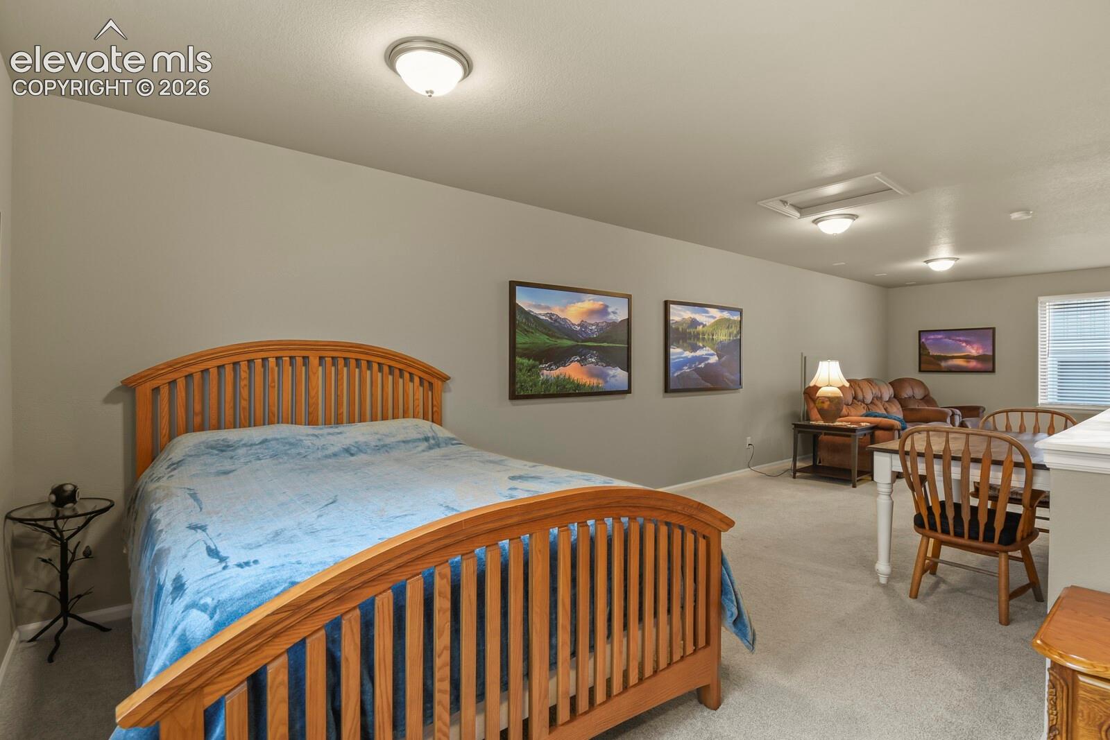 Expansive room featuring neutral wall paint, carpeted flooring, multiple flush-mount ceiling lights, and a window with horizontal blinds