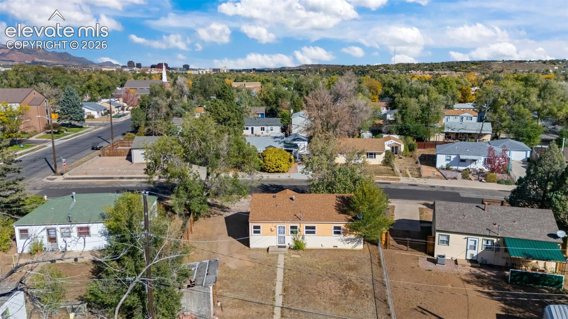 Aerial perspective of a detached single-story residence with a pitched shingle roof, exterior masonry siding, and a fenced perimeter lot