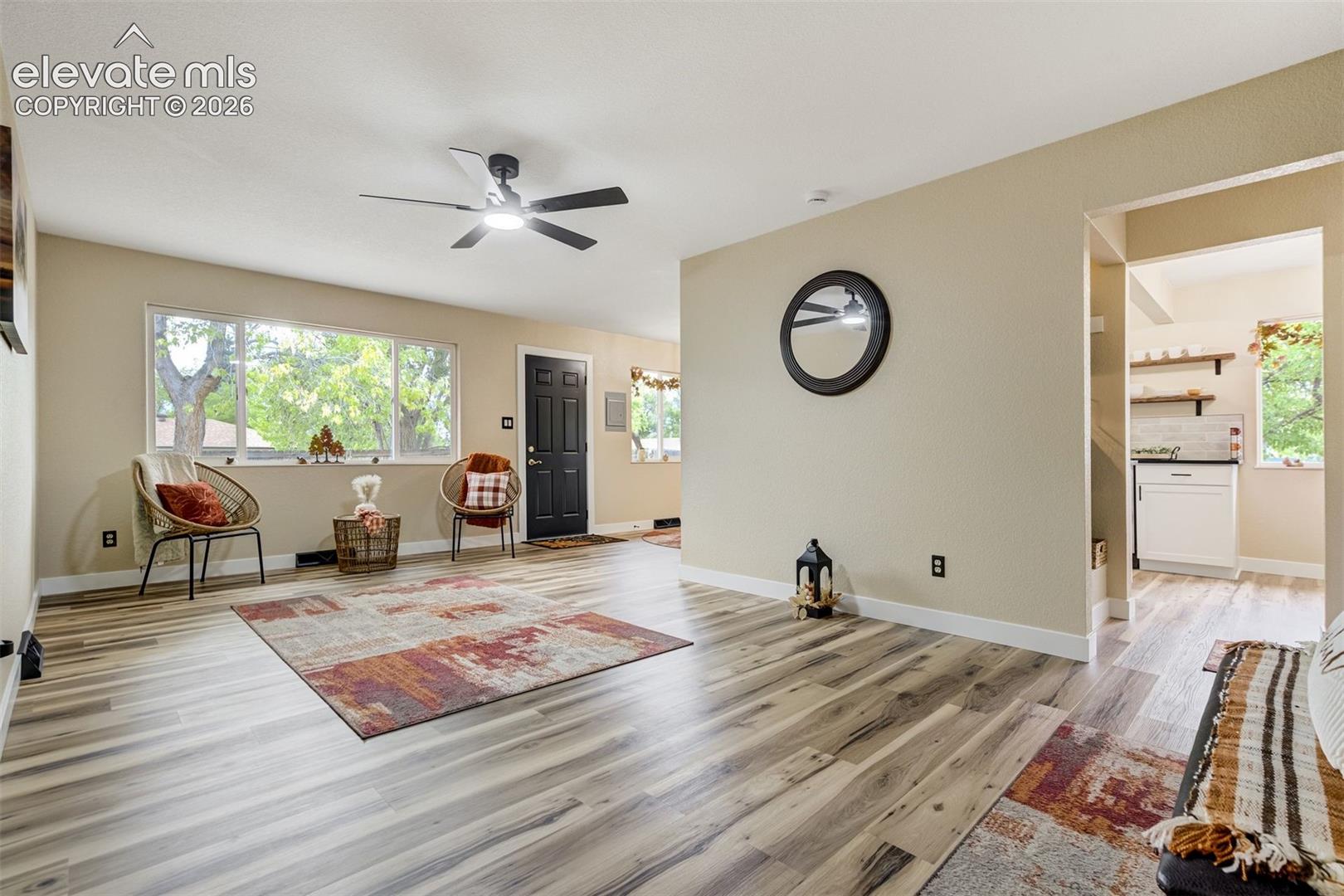 Living room with views of Pikes Peak out the large window. Door leads to the gated, 2nd driveway and oversized 2 car garage. Thoughtful shelving and lights by the hallway leading into the kitchen and breakfast nook.