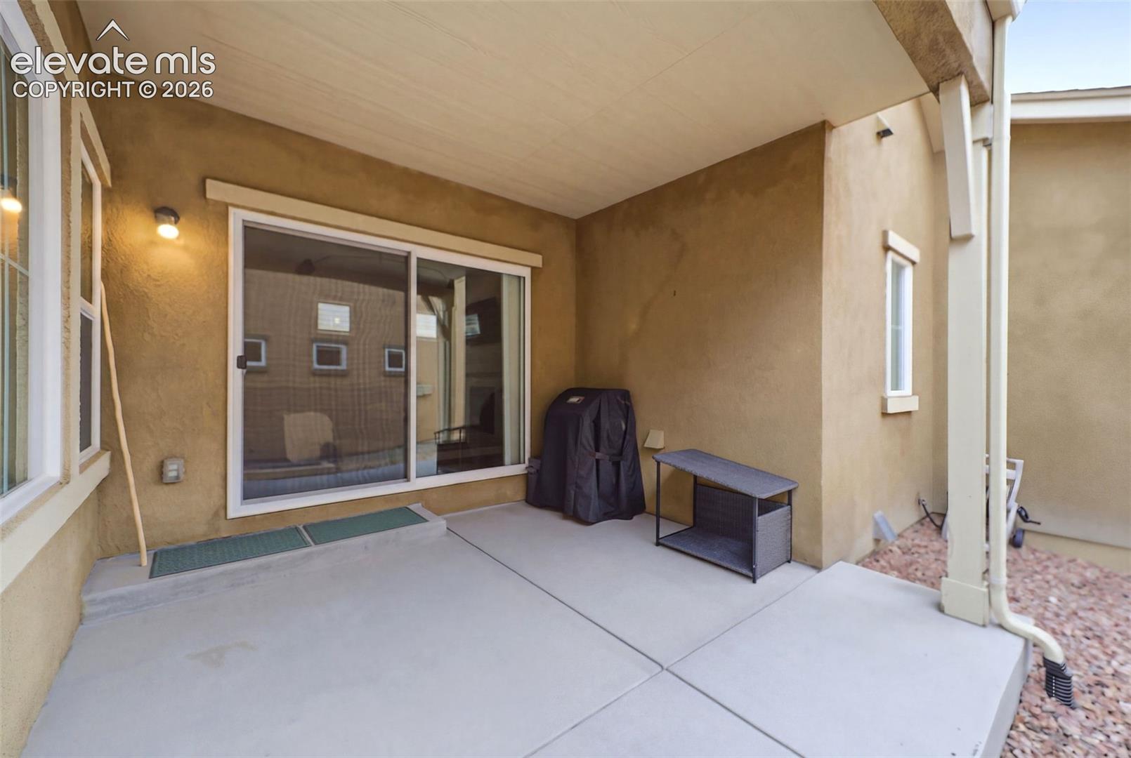 Covered patio with concrete flooring, stucco exterior, and sliding glass door access