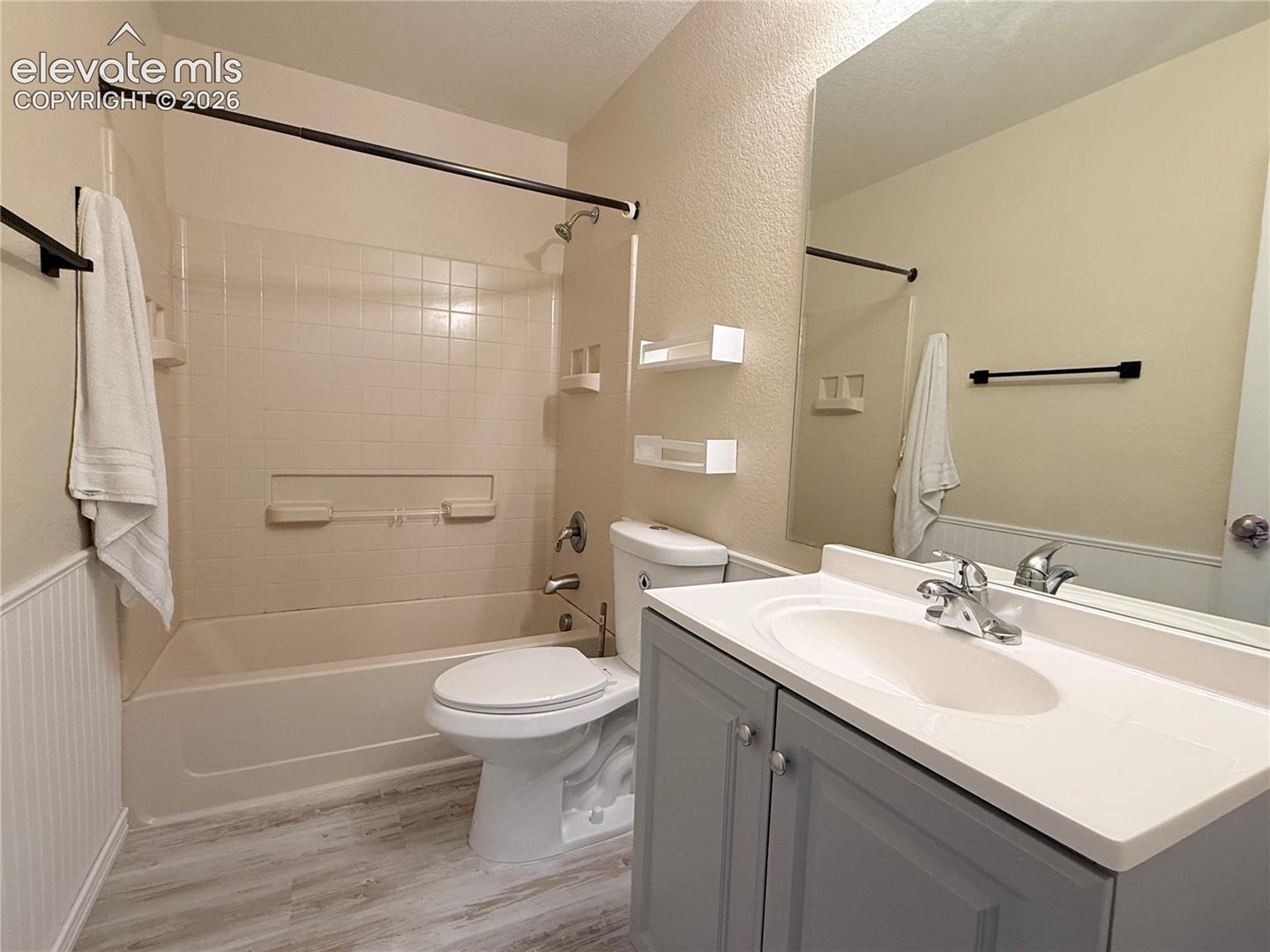 Full bathroom featuring a tub/shower combination with tiled surround, a toilet, and a vanity with a single basin sink