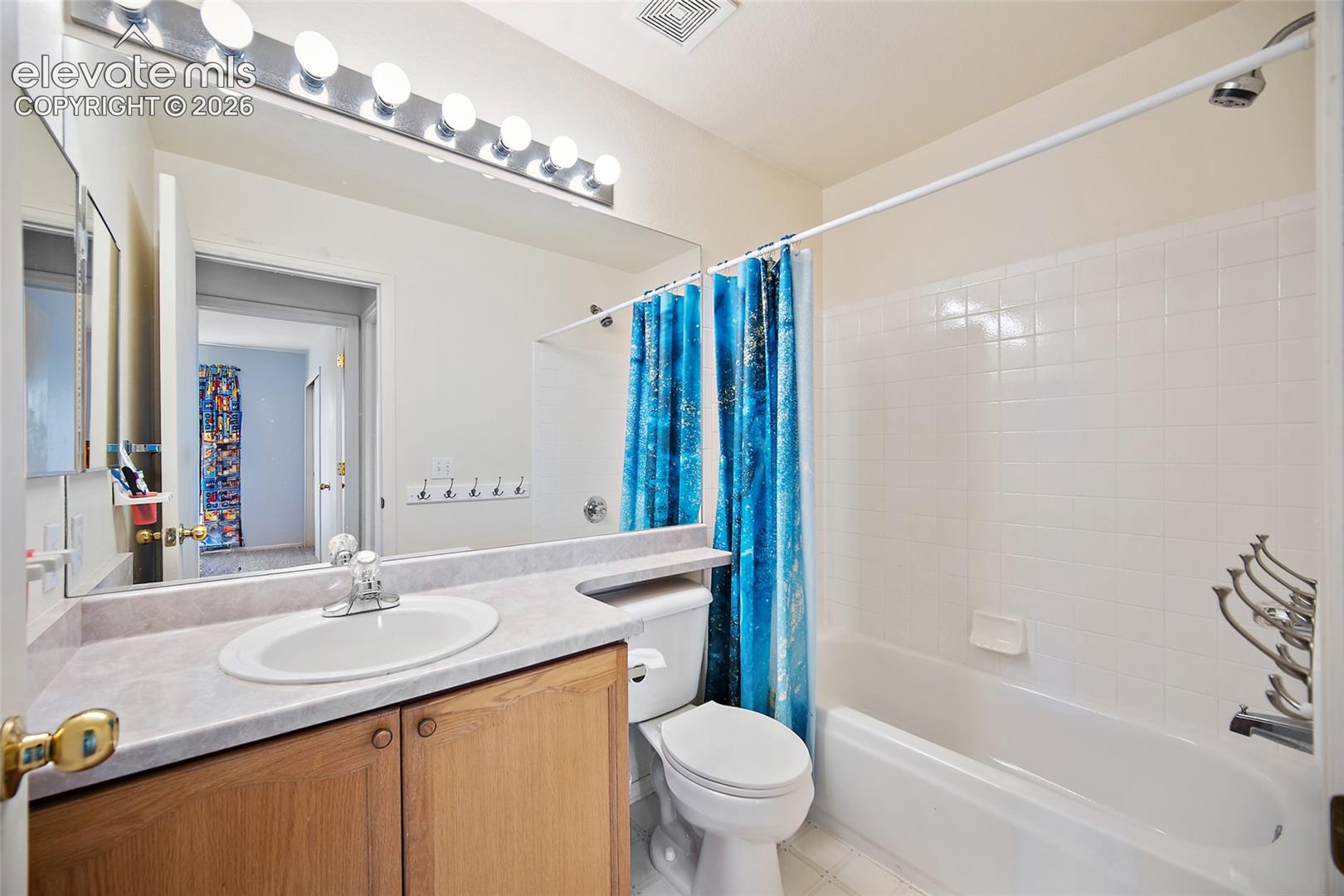 Bathroom featuring a wood-finish vanity with an integrated sink and laminate countertop