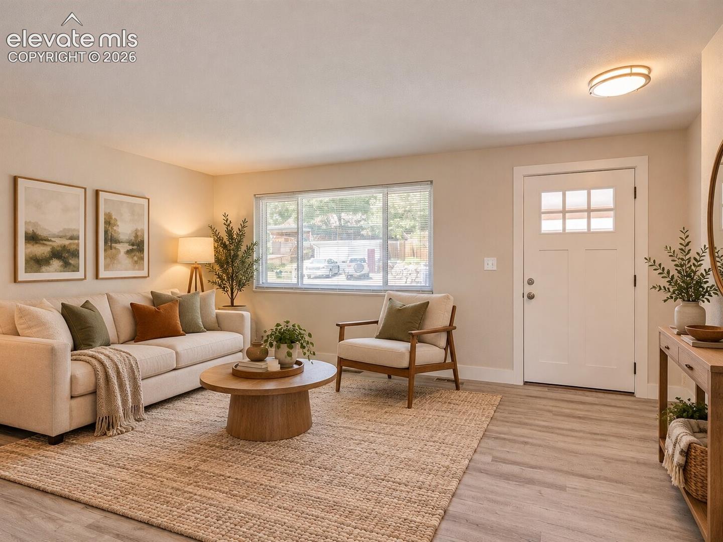 Neutral color palette featuring wood-finish flooring, a large picture window, and a multi-pane glass entry door with a rounded ceiling-mounted light fixture. AI-Enhanced – furniture/decor digitally added