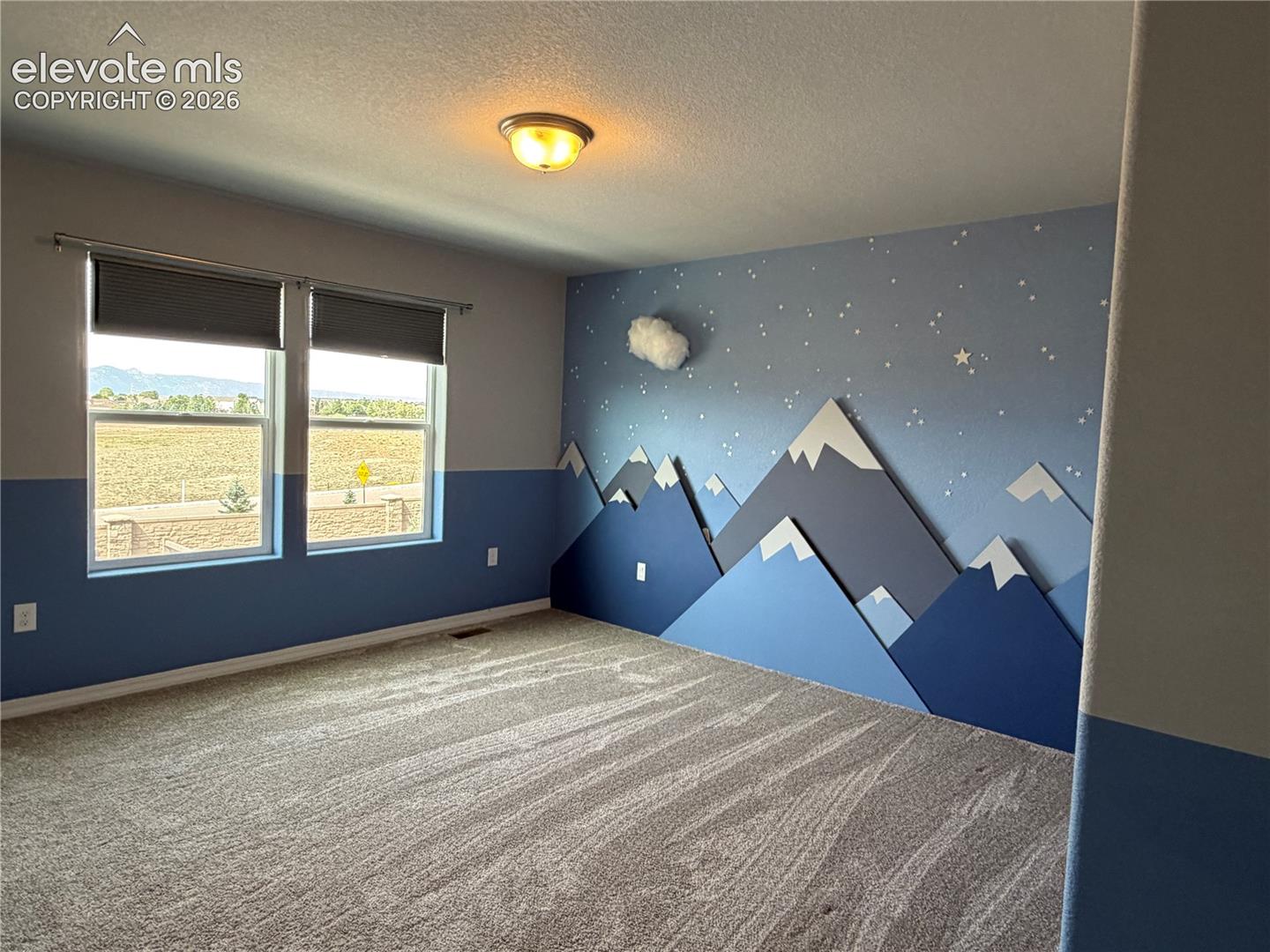 Carpeted flooring, recessed double windows, wall-mounted light fixture, and an accent wall with mountain-themed detailing