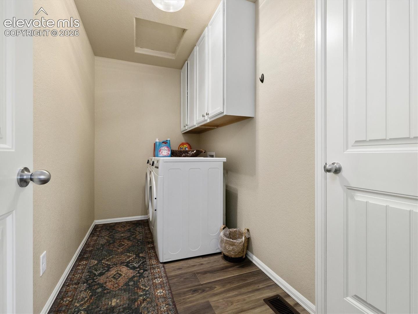Upper level. Laundry area featuring LVP flooring, white cabinetry, and light-toned walls