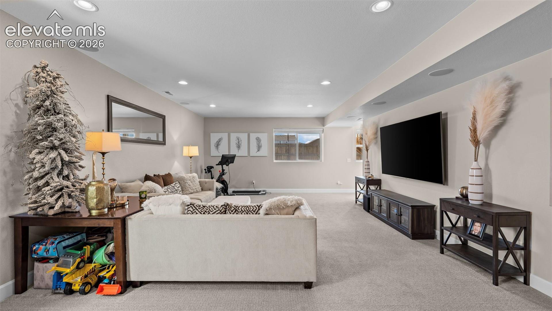 Recessed lighting, light-colored carpeting, multiple windows, built-in speakers, and neutral wall tones