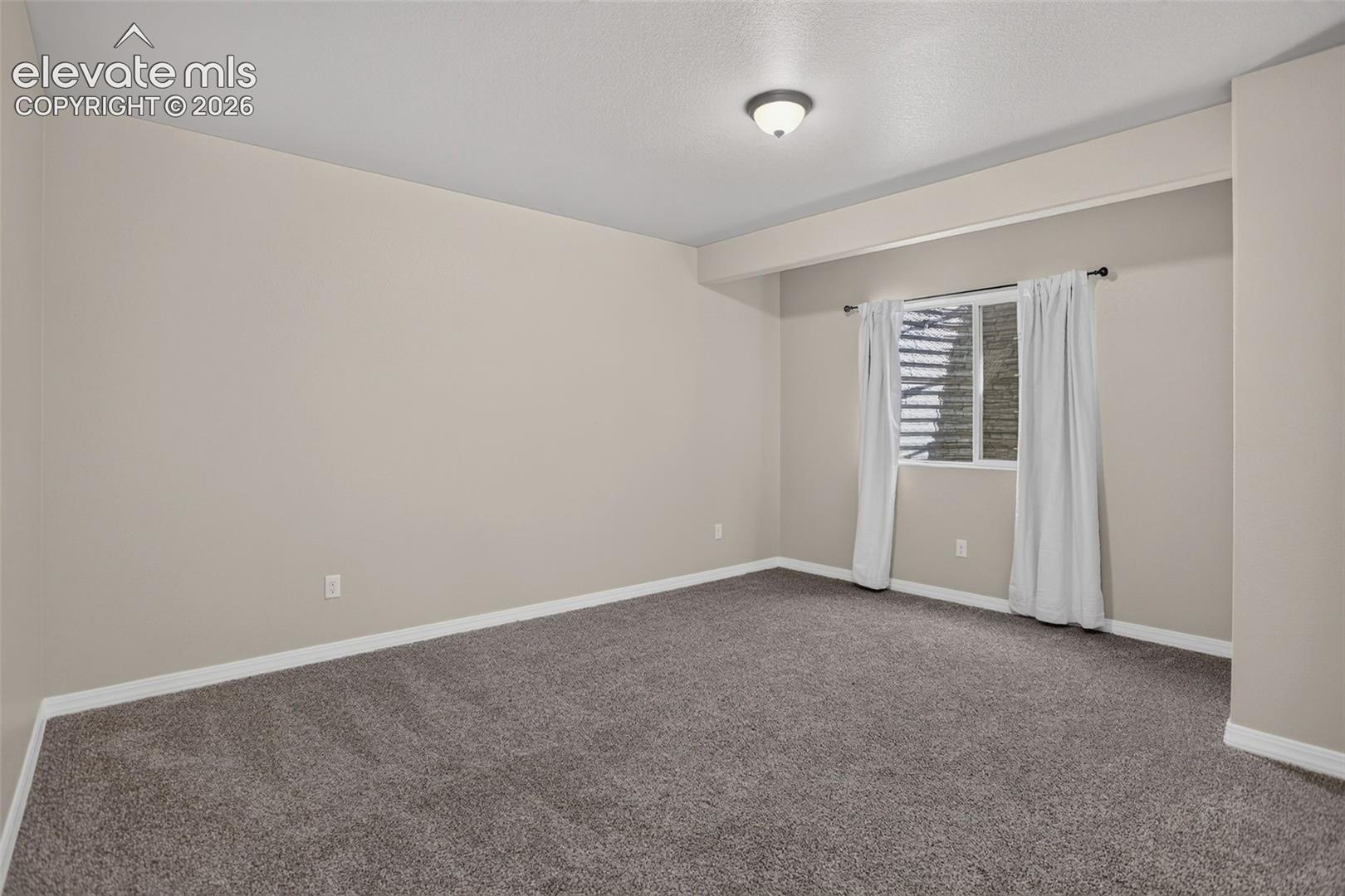 Recessed ceiling light, neutral wall color, window with horizontal blinds, gray carpet, white trim