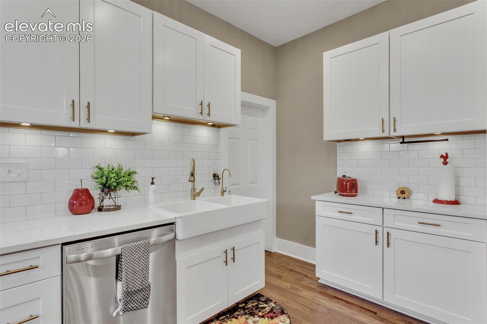 Kitchen featuring white shaker-style cabinetry, a white subway tile backsplash, and light-toned countertops