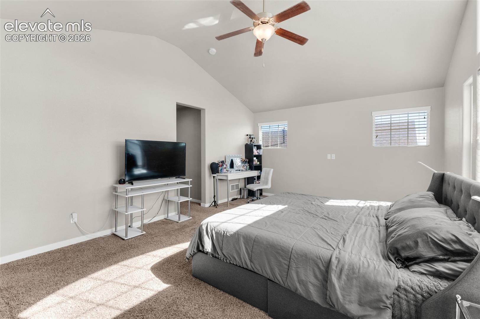 Vaulted ceiling, ceiling fan with integrated lighting, neutral wall palette, and dual windows