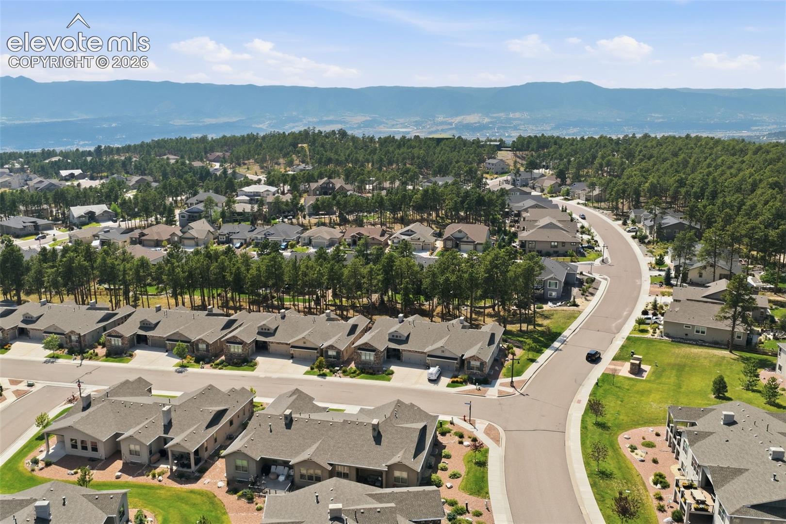 Residential community featuring paved streets, mature trees, and mountainous terrain in the background.