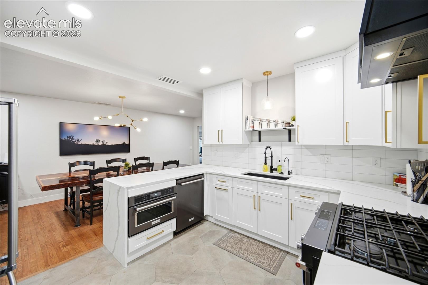 The remodeled kitchen features black stainless appliances and and quartz countertops with a waterfall detail. A gas range and lots of storage bring modern convenience to this mid-century masterpiece. 