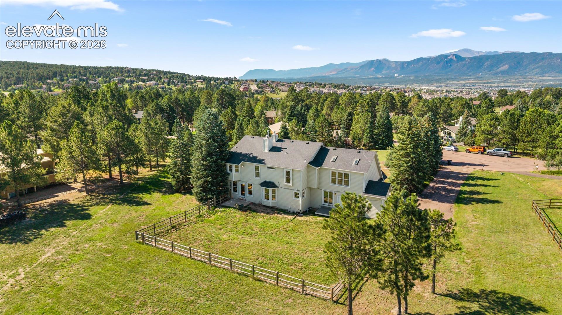 Expansive property featuring a multi-story residence, mature trees, and a mountain backdrop