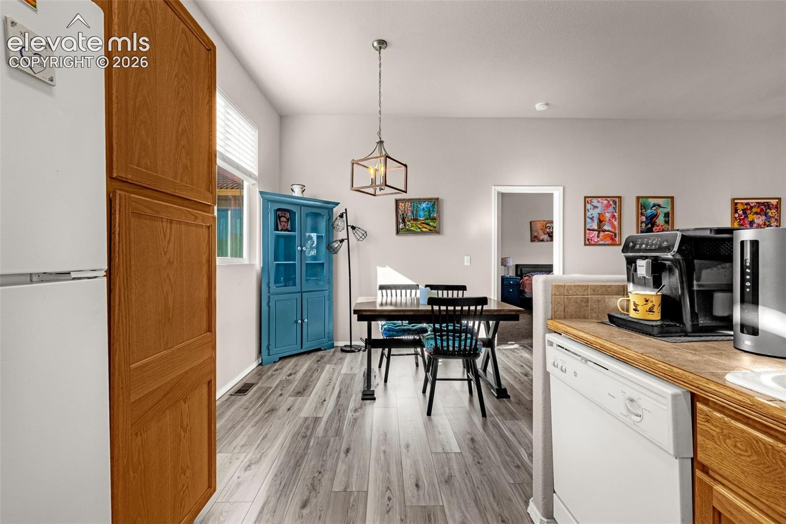 Wood-finish flooring, geometric-frame pendant lighting, and neutral wall tones