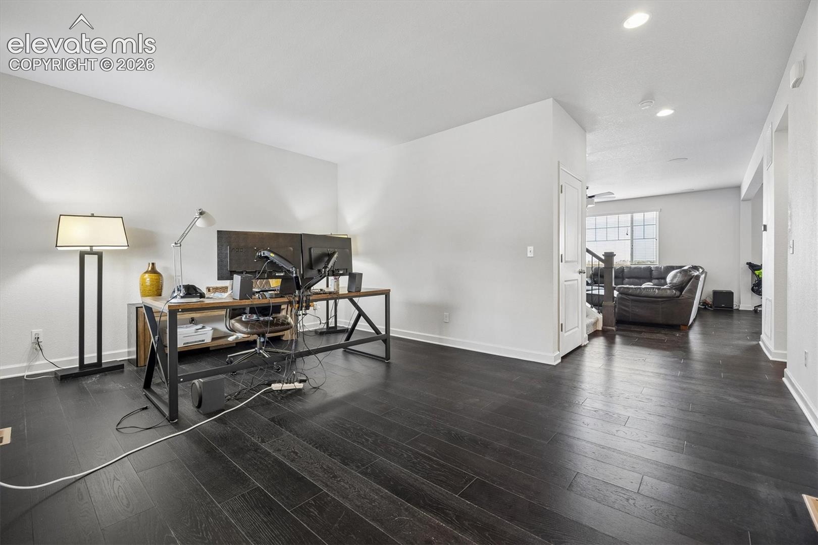 Spacious room featuring dark wood-finish flooring, white baseboards, and recessed lighting