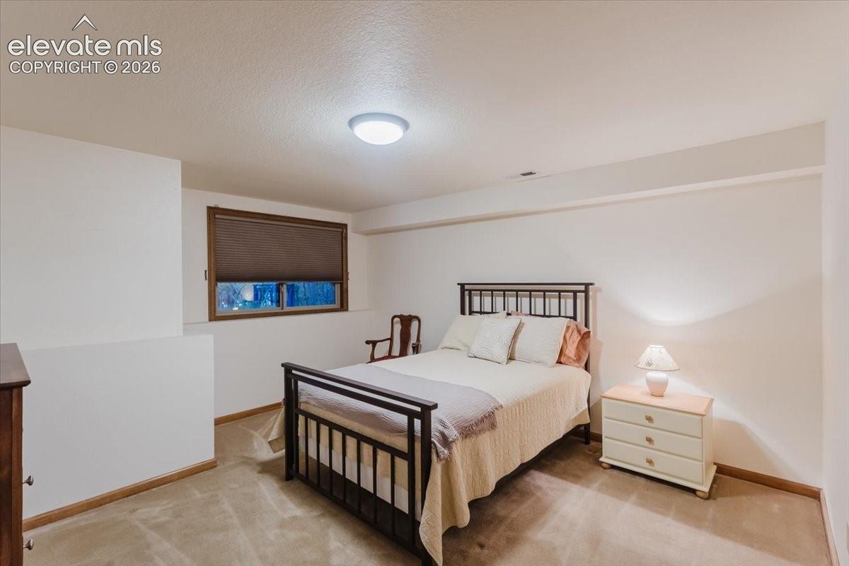 Carpeted room featuring a window with a brown blind, white walls, and a ceiling-mounted light fixture