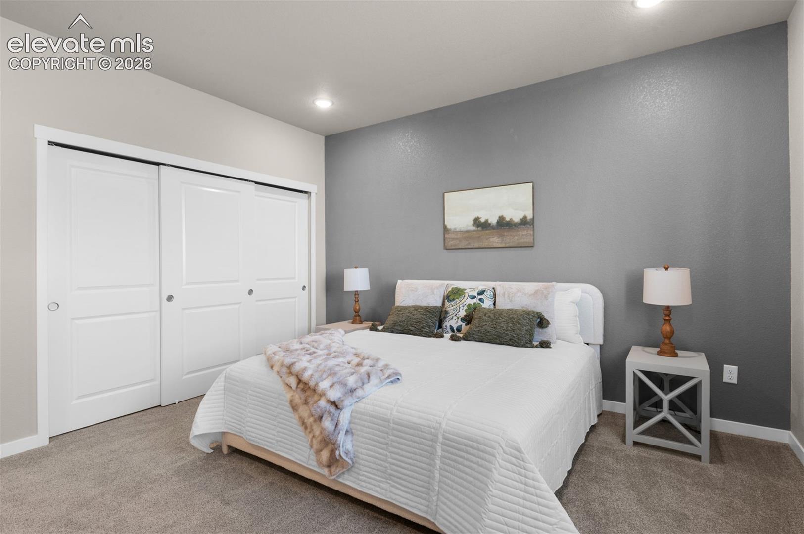 Recessed ceiling lighting, textured accent wall, light-colored walls, white trim, and neutral carpet flooring