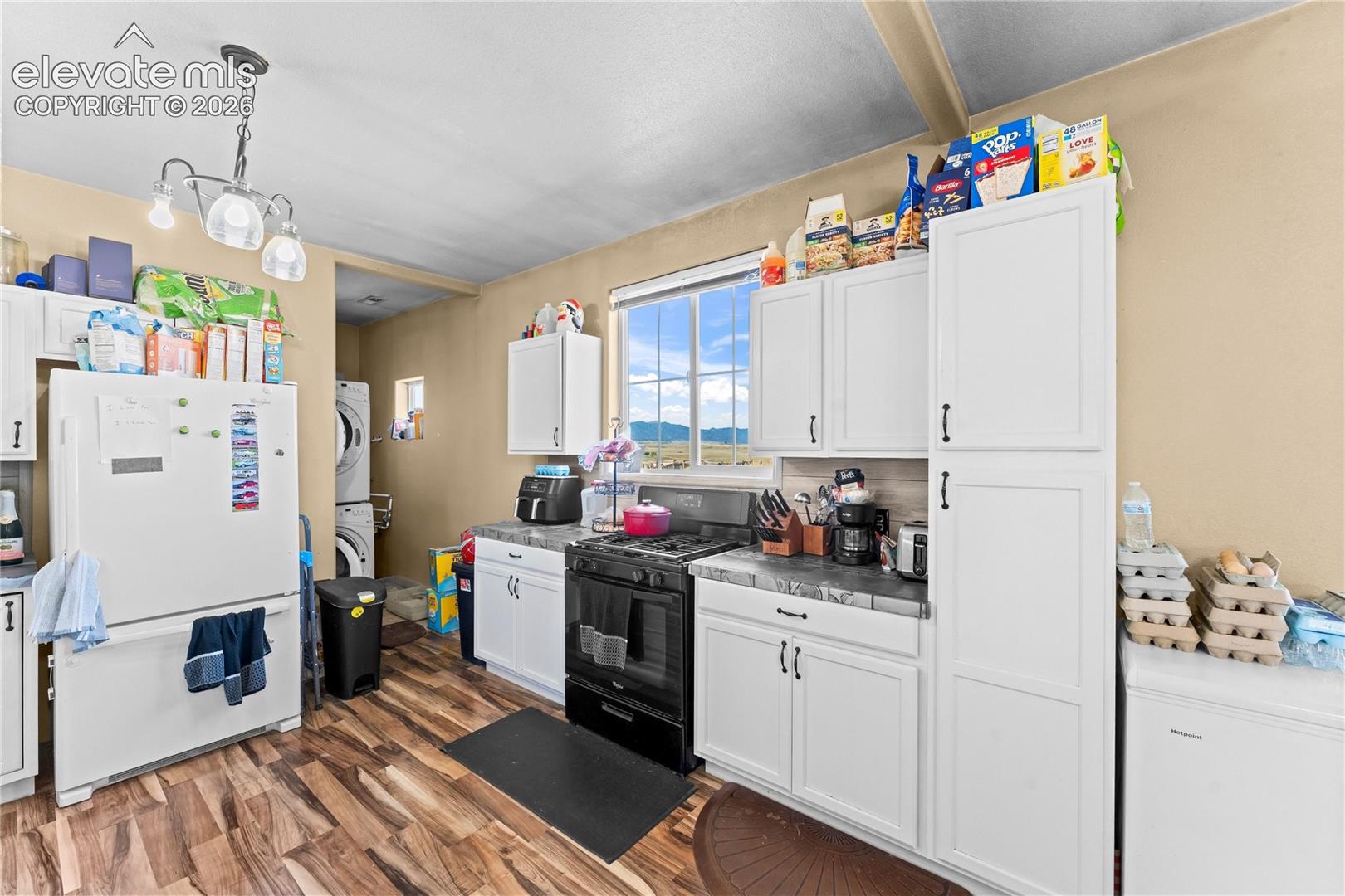 Kitchen featuring white cabinetry, wood-finish flooring, a stone-pattern laminate countertop, and a multi-arm chandelier