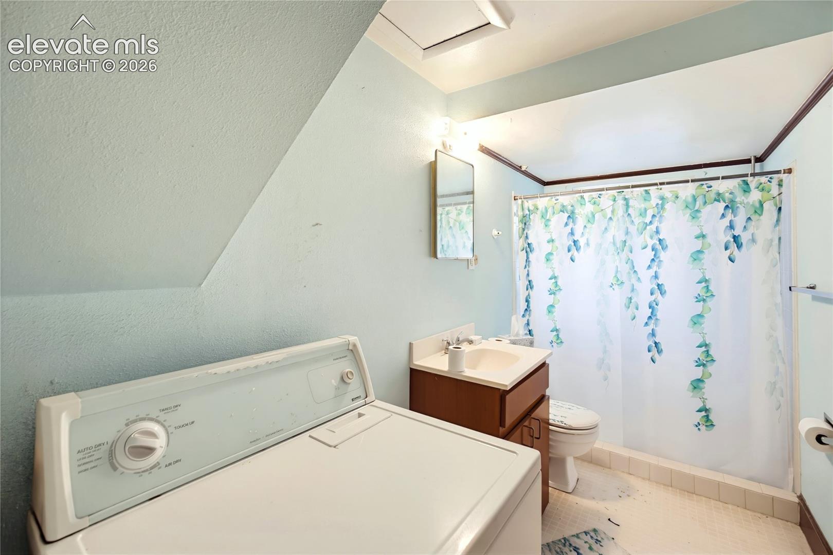Compact bathroom with a built-in vanity, white sink, and tiled flooring