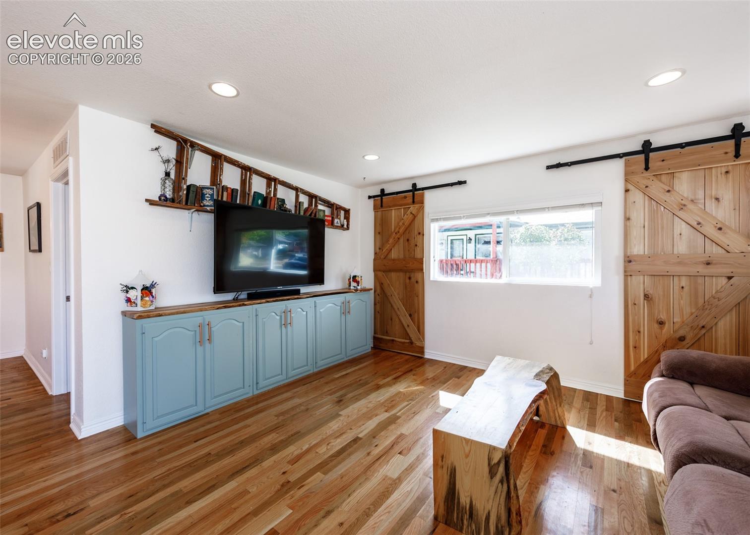 Wood flooring, recessed lighting, built-in cabinetry with a wood countertop, and dual barn doors with black hardware