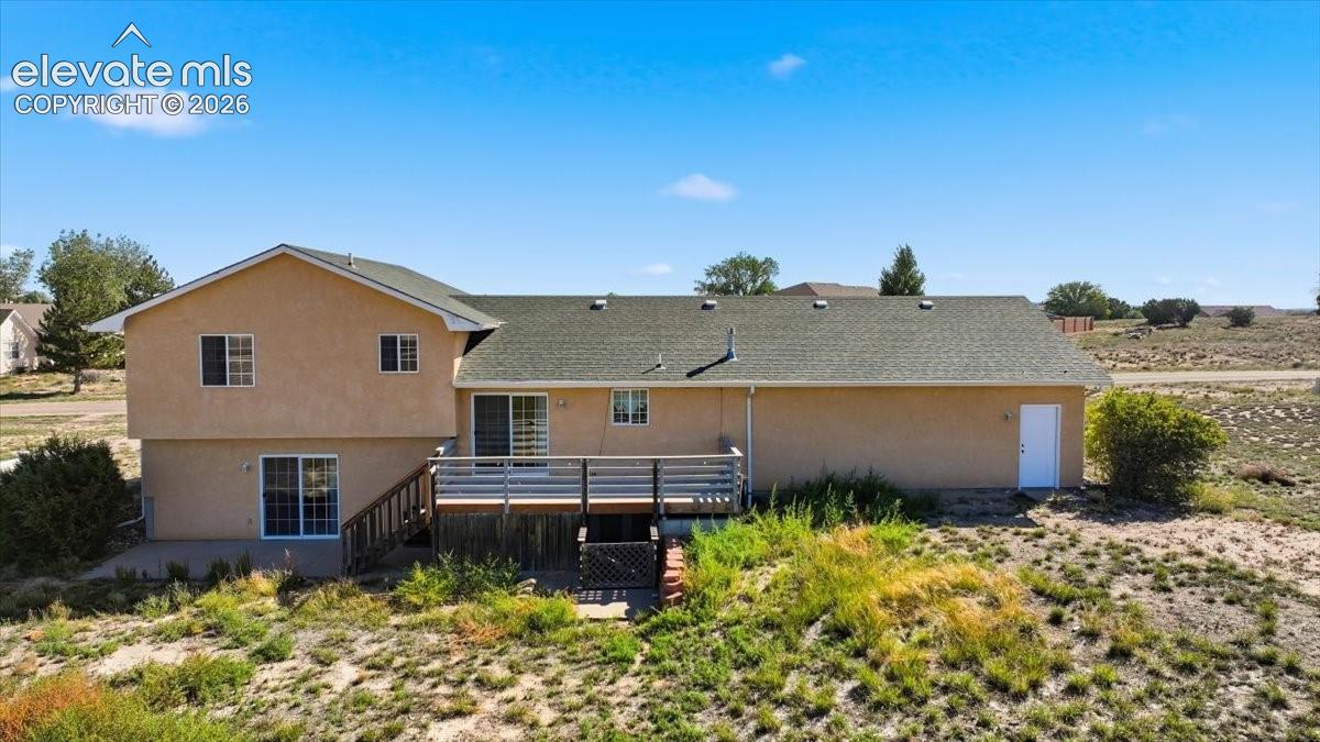Rear exterior with a multi-level deck, multiple sliding glass doors, and a ground-level patio