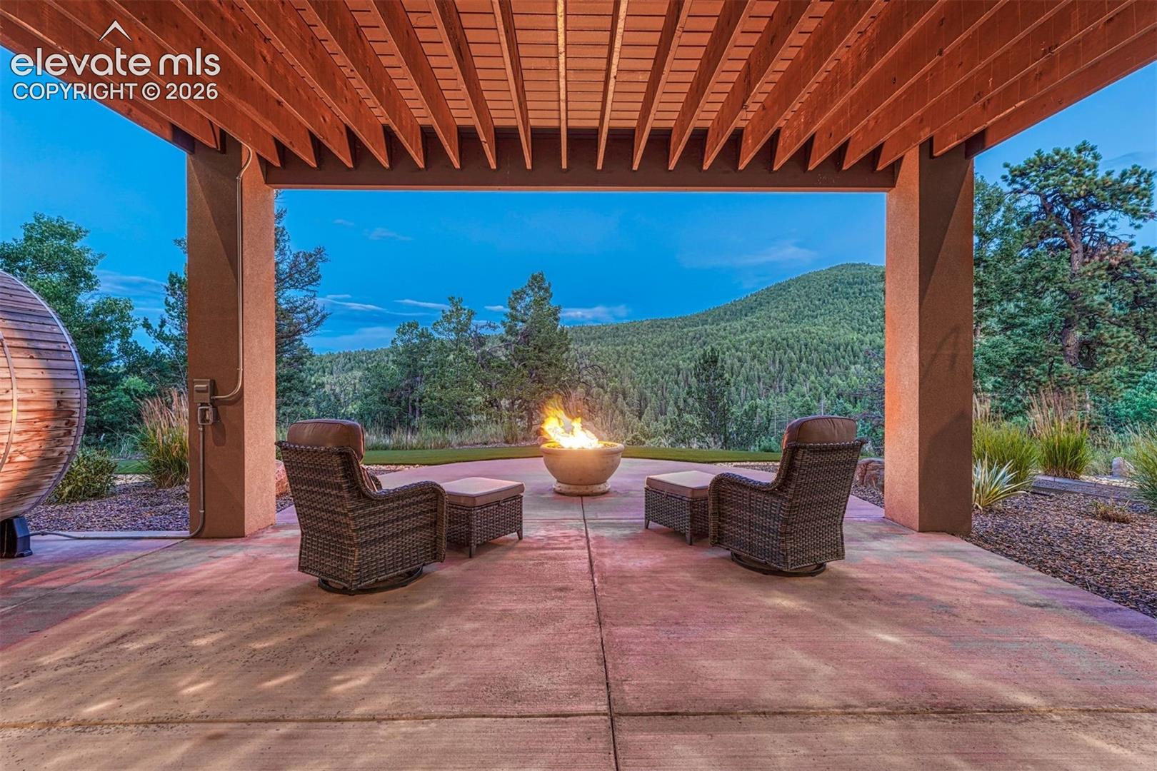 Covered patio with a wood-slat ceiling, concrete flooring, and an integrated fire pit
