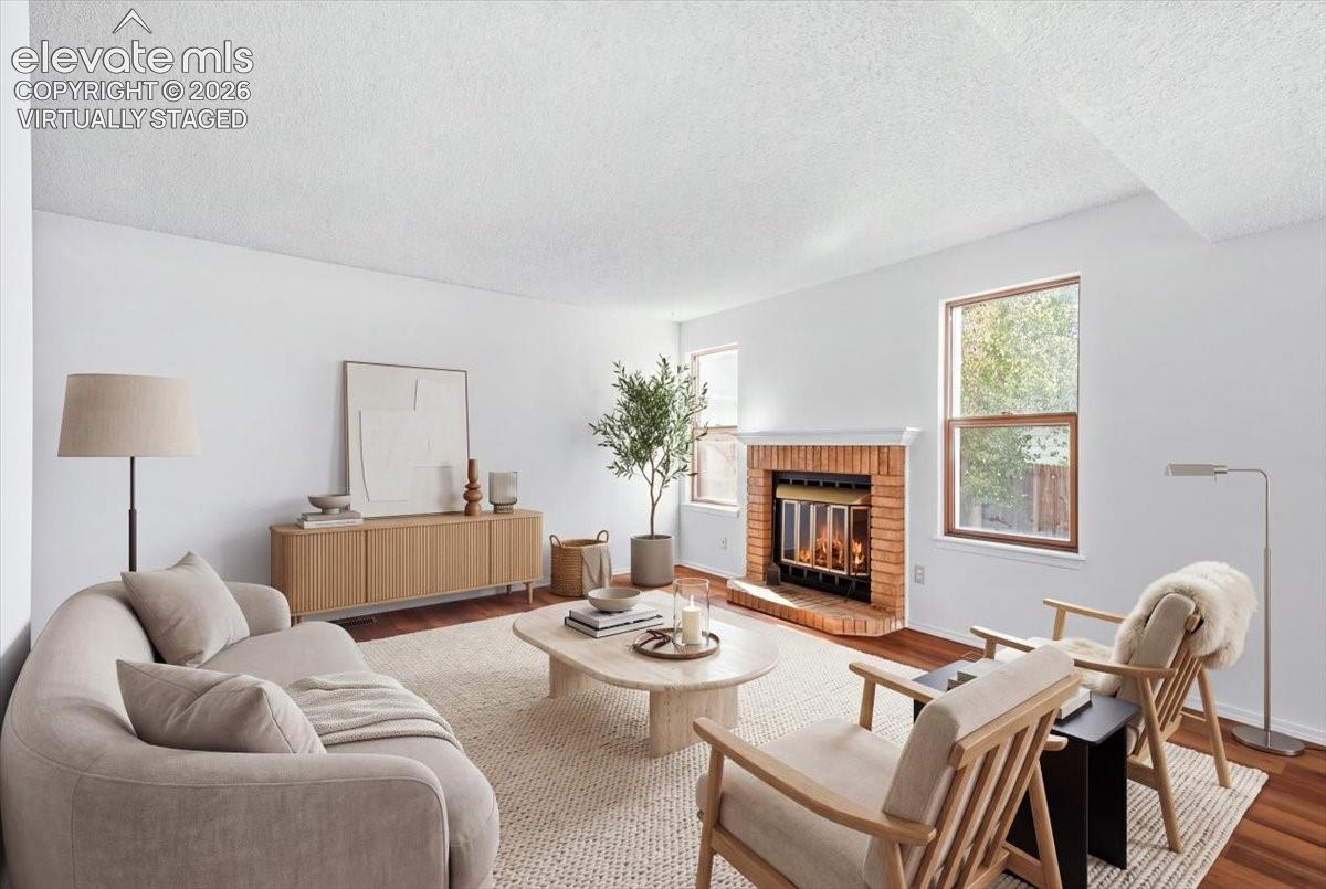 Virtually staged living room with a wood-burning fireplace and new LVP flooring at , Colorado Springs, CO. 