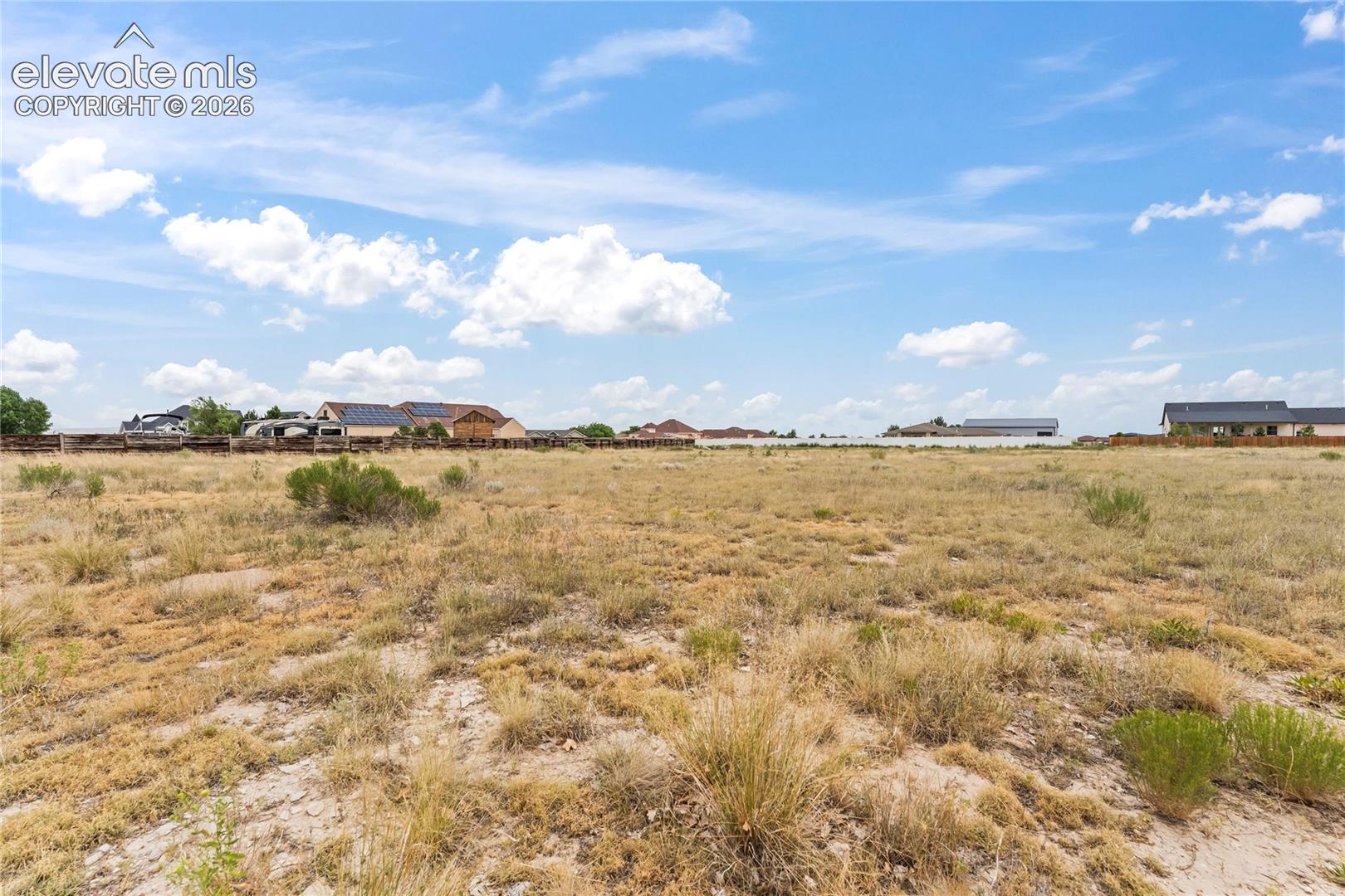 Expansive parcel of land featuring open terrain and a horizontal wooden perimeter fence