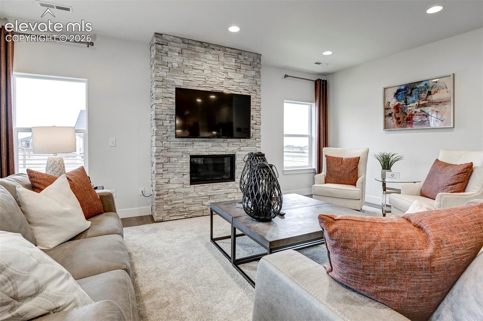 Stone-finish fireplace surround with integrated fireplace, recessed lighting, wood-finish flooring, and light-toned wall paint