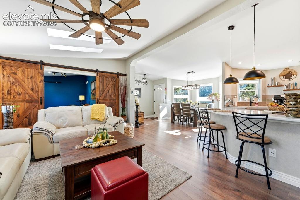 Wood-finish flooring throughout, featuring a kitchen island with pendant lighting and bar seating