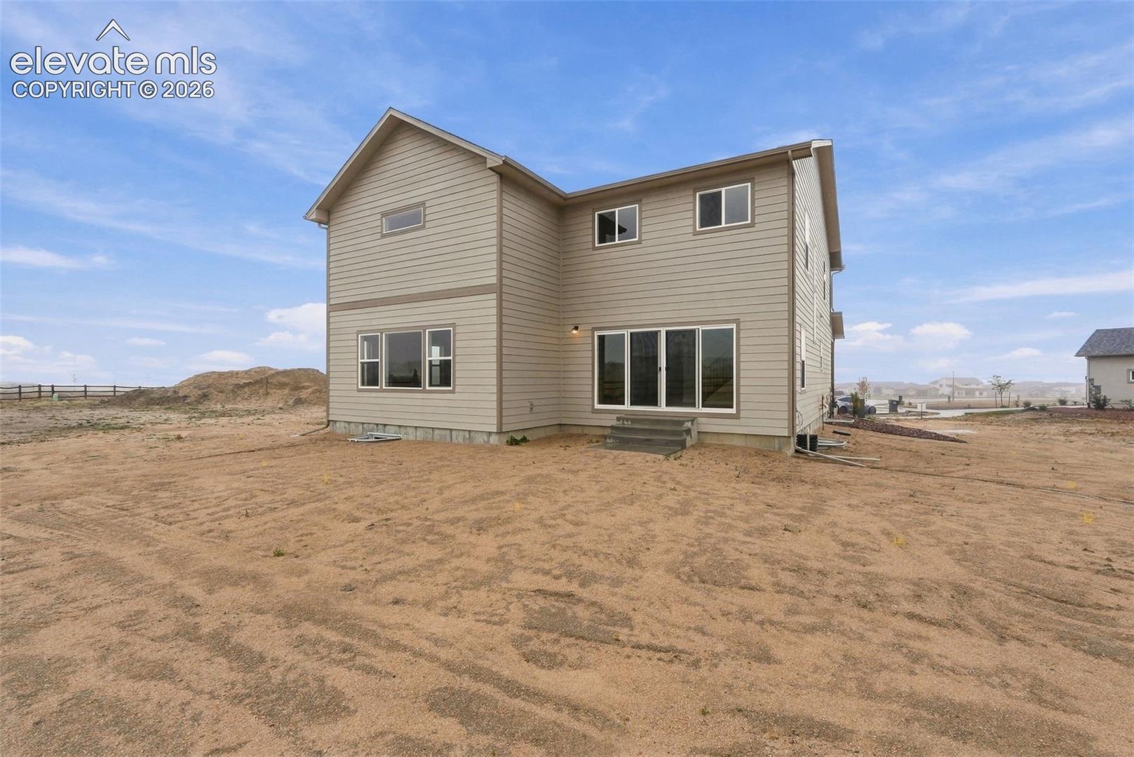 Two-story residence featuring light-colored horizontal lap siding, a concrete foundation, multiple dual-pane windows, and a sliding glass patio door