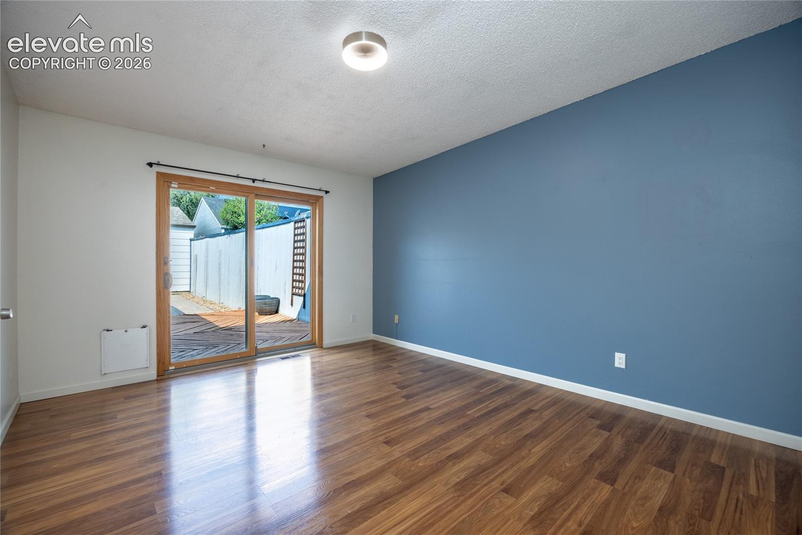 Wood-finish flooring, two-tone wall paint, and a sliding glass door with wood trim