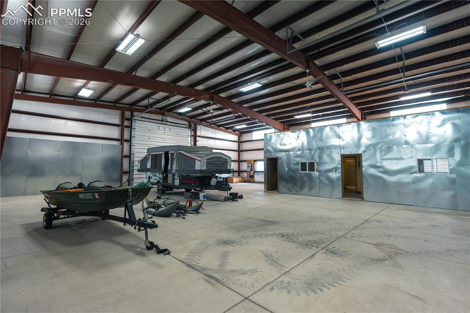 Spacious commercial building featuring a large open area, a high ceiling with exposed metal beams, and concrete flooring