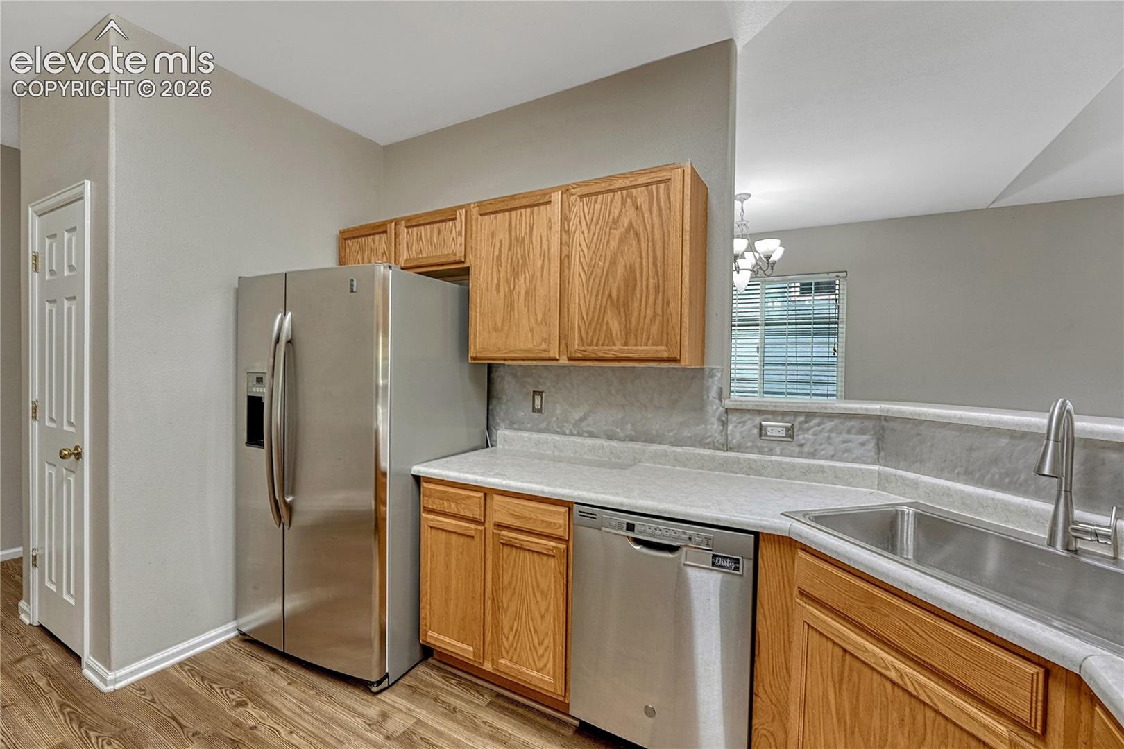 Kitchen featuring natural finish cabinetry, light-toned countertops, stainless steel appliances, and wood-finish flooring