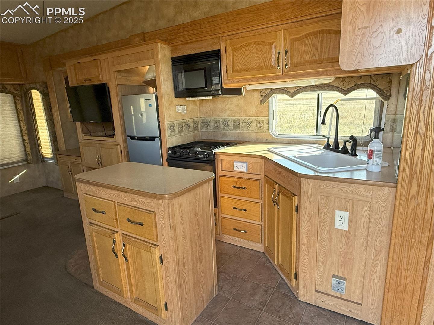 Kitchen featuring light countertops, black appliances, and a kitchen island