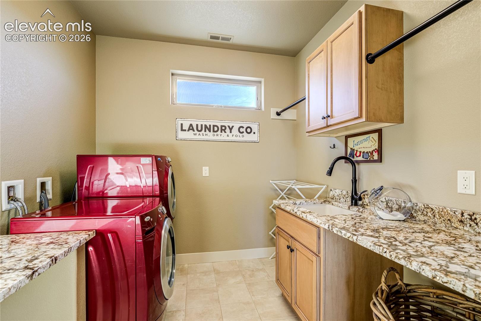 Conveniently located upstairs, the expansive laundry room features generous cabinetry, a utility sink + a granite-topped folding counter. A window brings natural light to this thoughtfully designed everyday workspace.