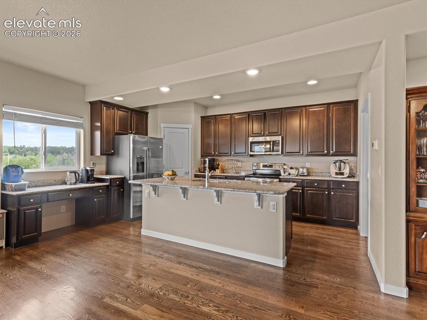 Spacious kitchen featuring dark wood cabinetry, stainless steel appliances, and wood-finish flooring
