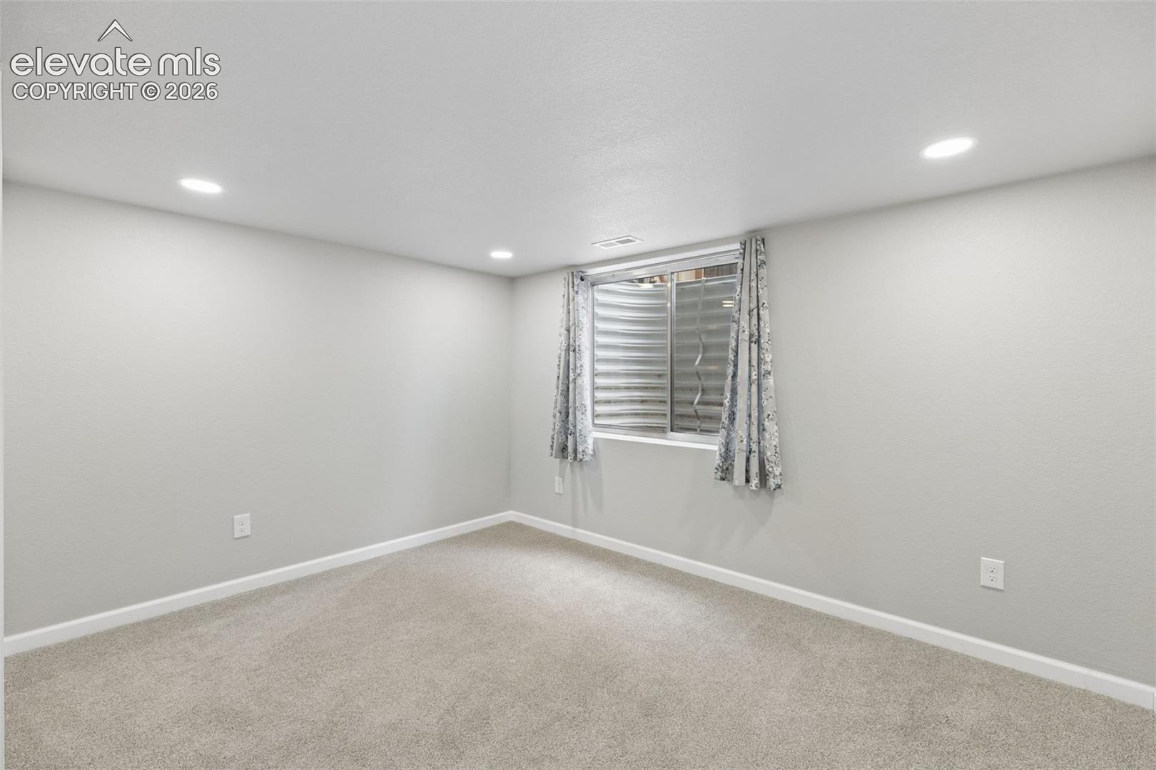 Neutral interior space featuring recessed lighting, wall-to-wall carpeting, and a sliding window with a window well