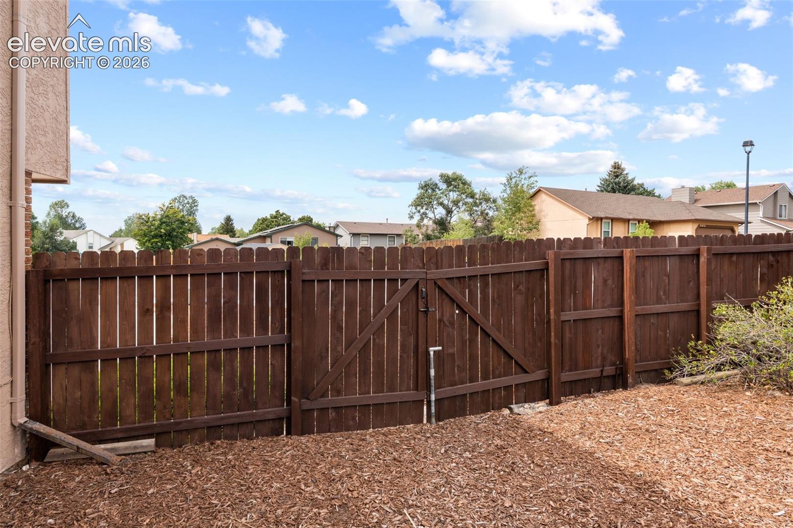 Stained wood privacy fencing with integrated double-gate entry and mulch ground cover