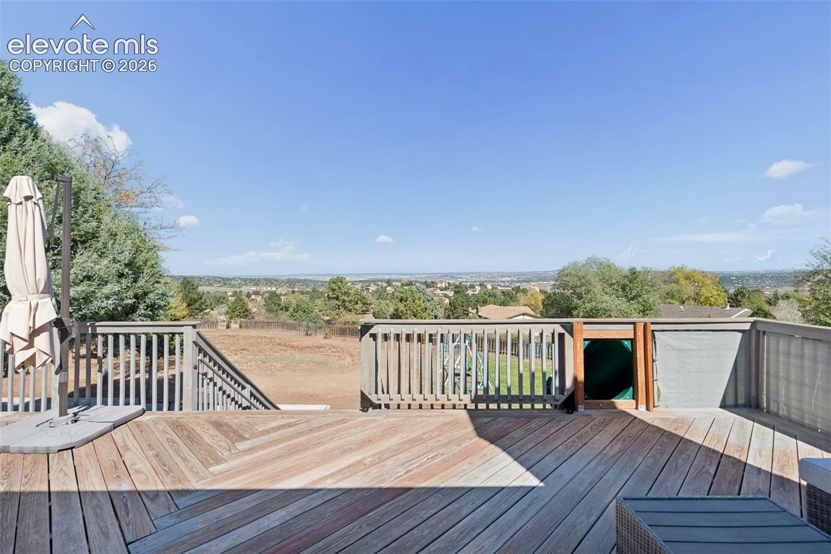 Elevated wood deck featuring vertical baluster railings, herringbone-patterned decking, and open-air space with long-range topography