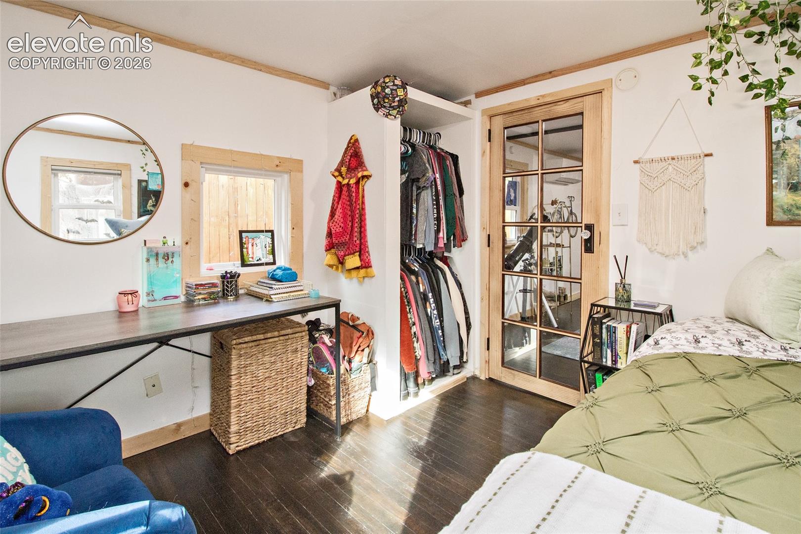 Wood-finish flooring, built-in open closet cabinetry, natural wood window trim, and a multi-pane glass door with a wood frame