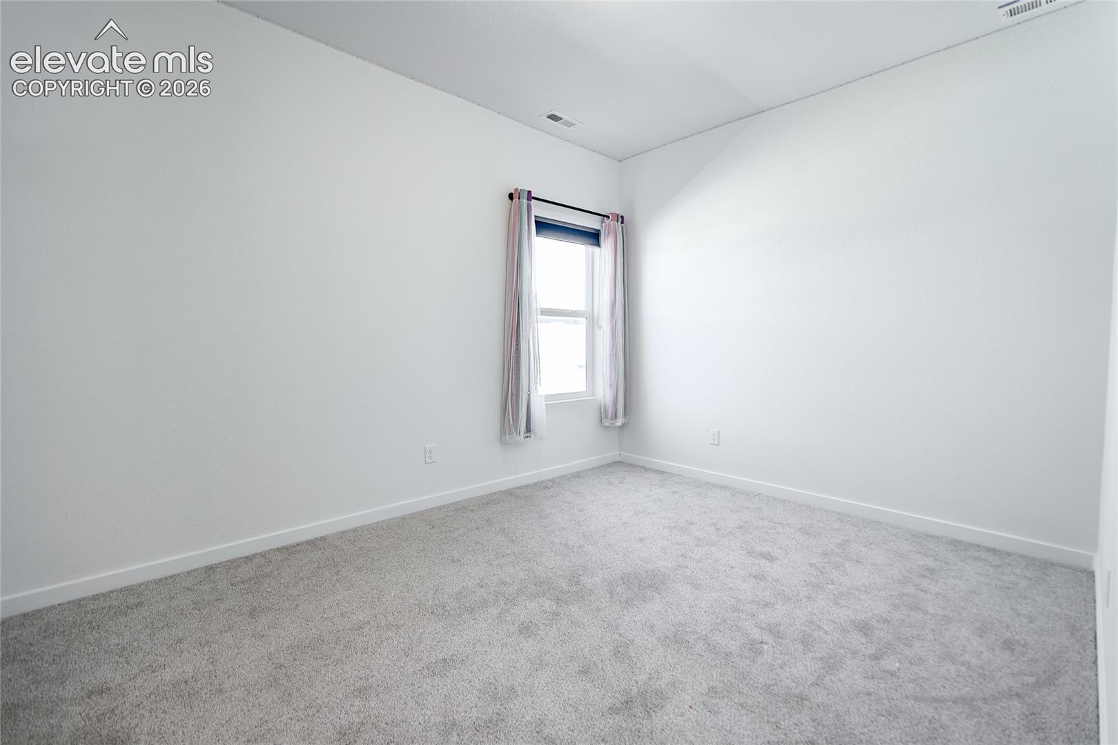 Room featuring neutral carpeting, high ceilings, and natural lighting provided by a single window