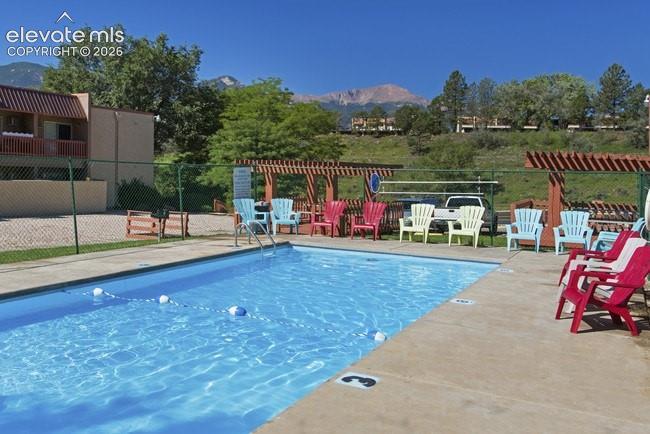 Outdoor swimming pool with integrated steps, concrete surround, and mountain backdrop