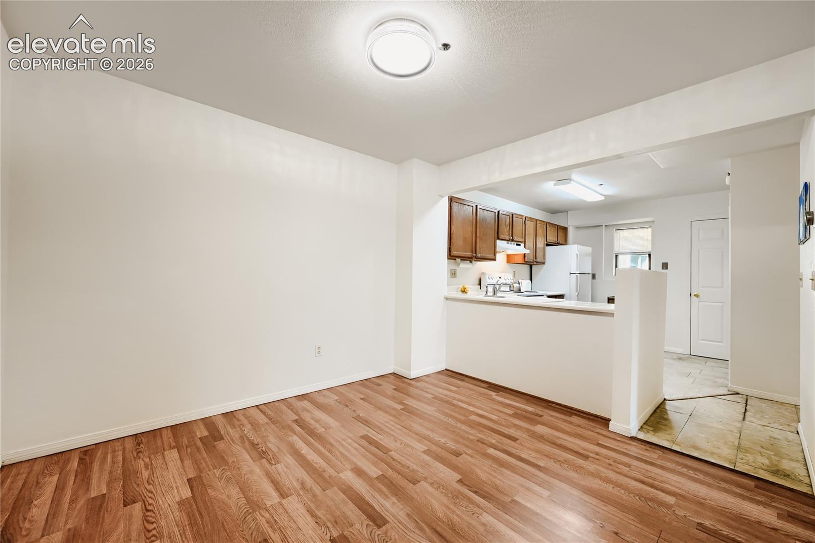 Spacious living area with warm wood-finish flooring, recessed ceiling lighting, and an open layout