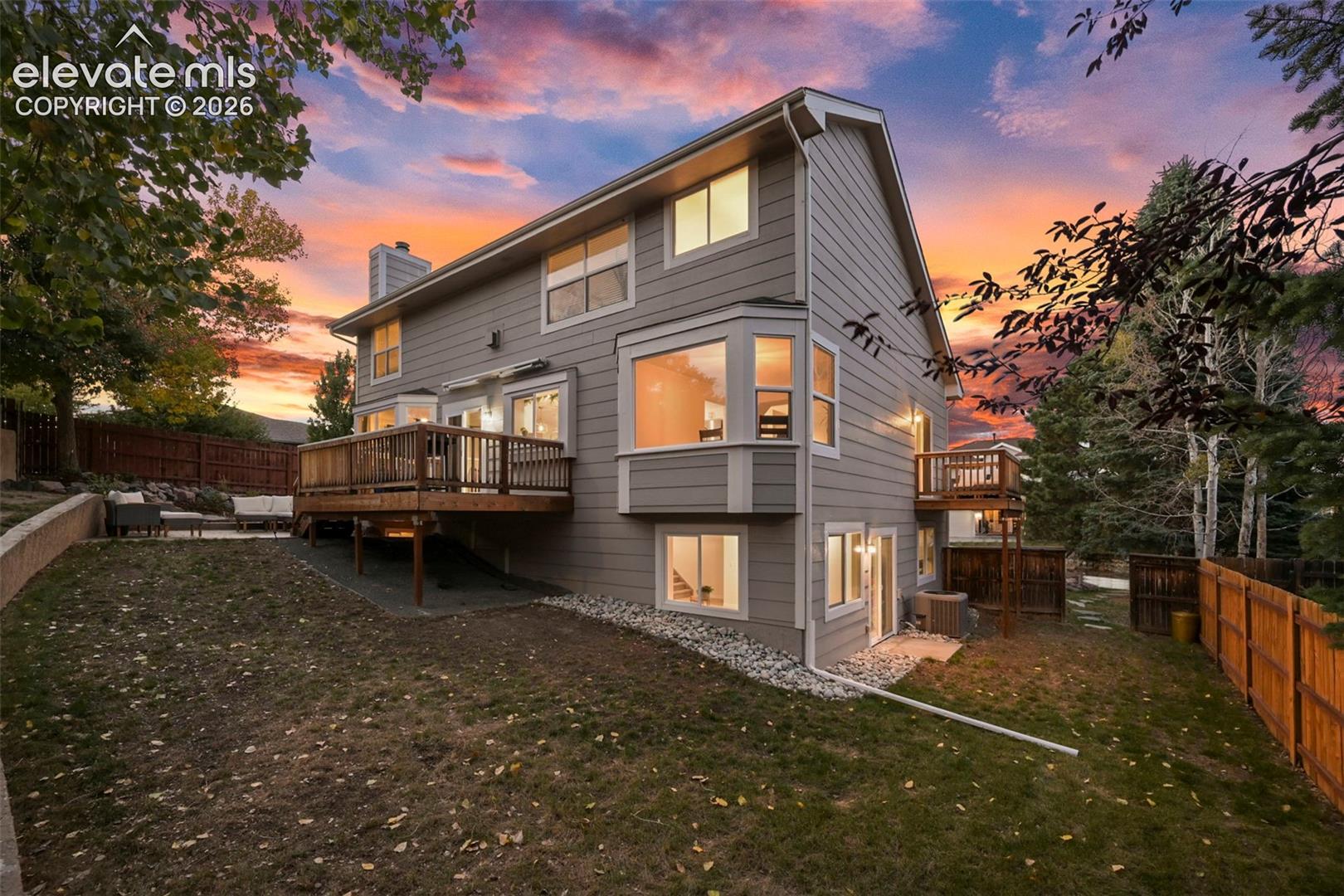 Multi-level residence featuring a wood-decked patio, bay windows, and a lower-level walk-out