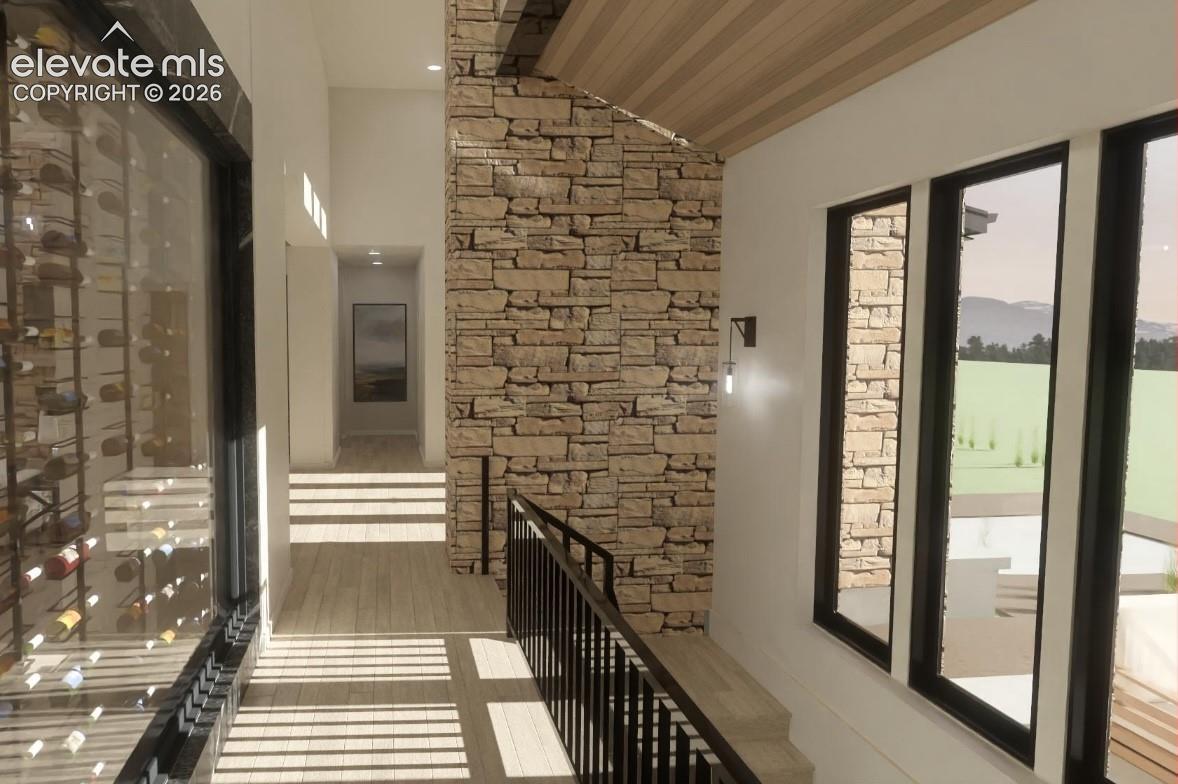 Stone accent wall, wood-finish flooring, black framed windows, black metal railing, glass-enclosed wine storage