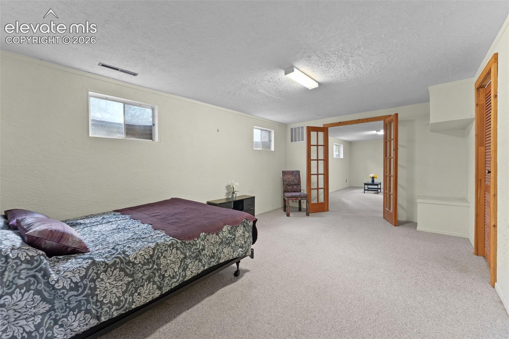 Carpeted flooring, recessed windows, wood-finish French doors, built-in shelving, and a built-in storage bench