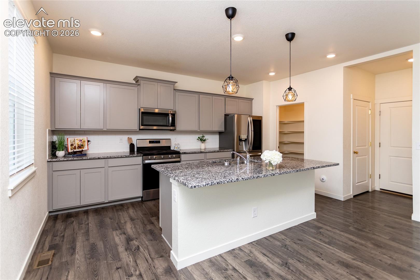 This beautiful kitchen offers granite countertops, subway tile backsplash, stainless appliances to include a gas range and an upgraded refrigerator. 